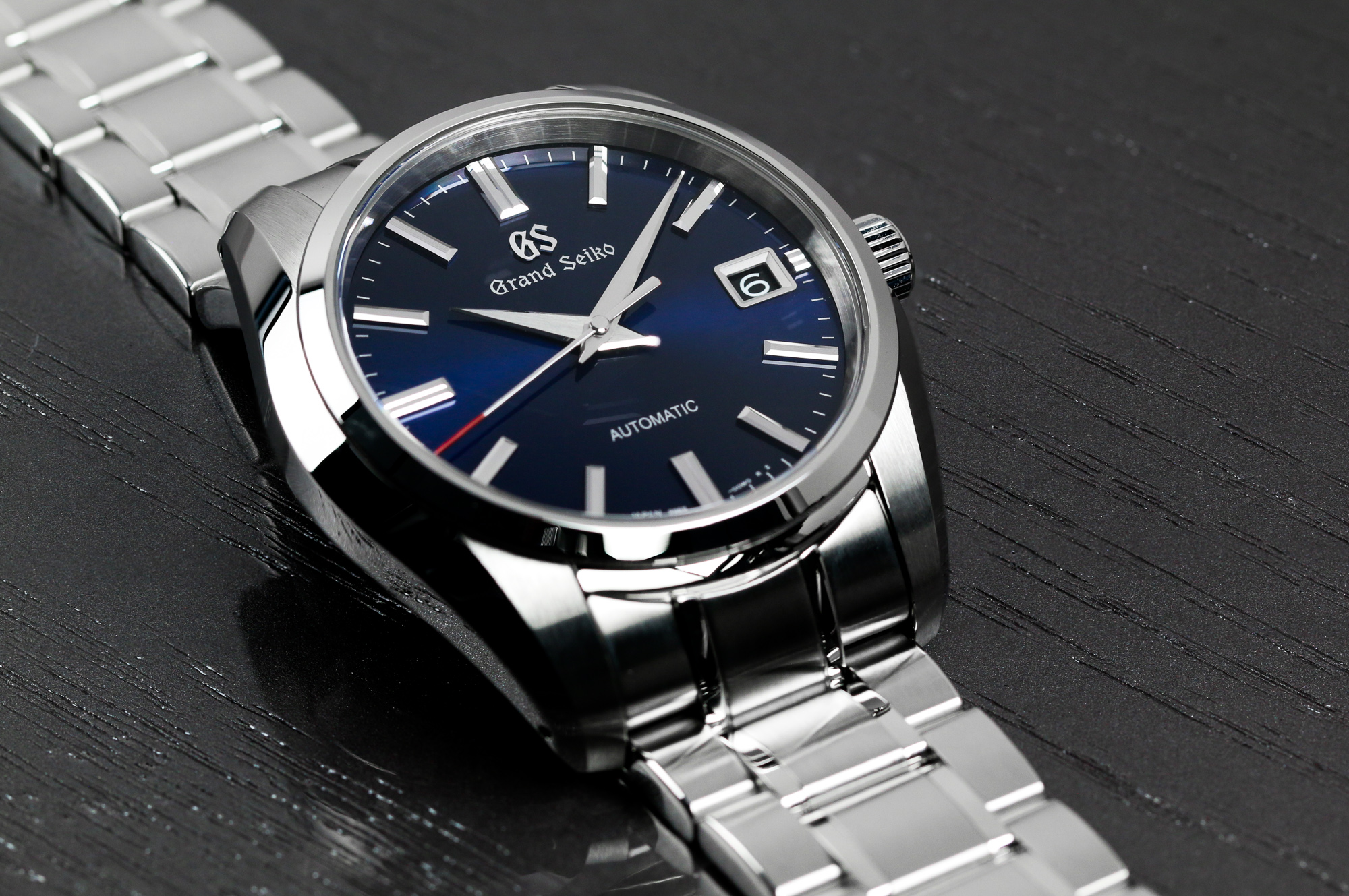 Grand Seiko SBGR321 wristwatch with a blue dial and red accents on a tabletop.
