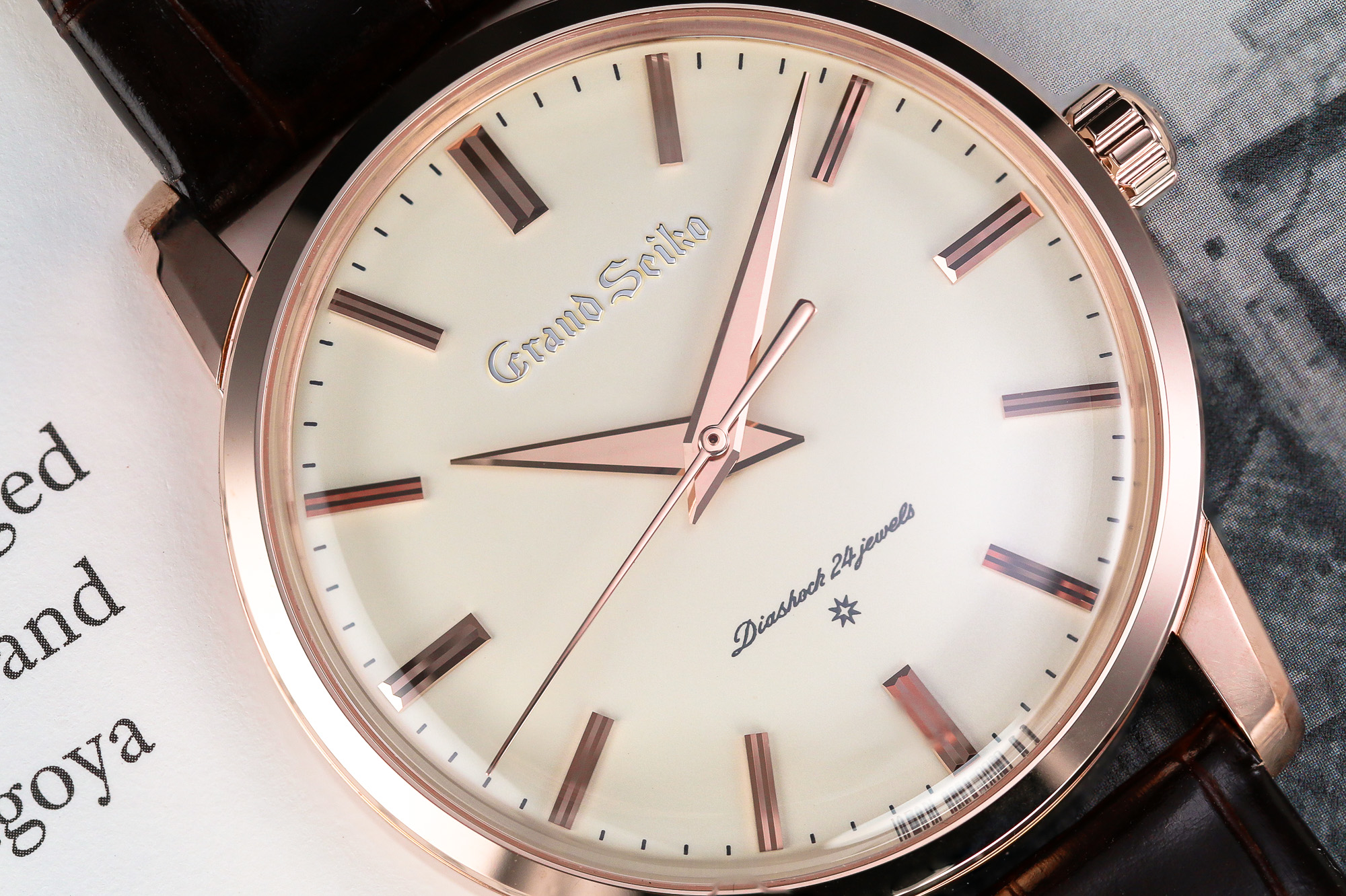 Grand Seiko SBGW260 gold case light dial wristwatch on a book.