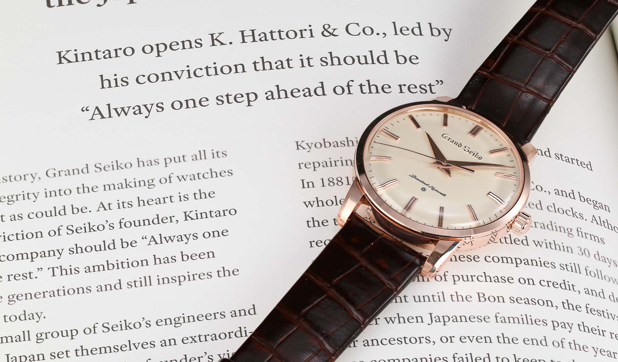 Grand Seiko SBGW260 golden dress watch laying on a book.